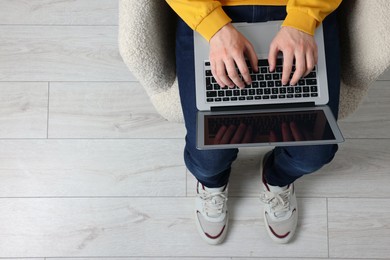 Photo of Man working with laptop in armchair, top view. Space for text