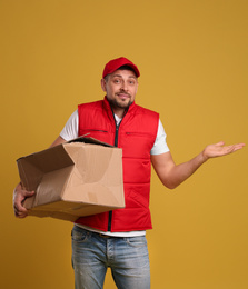 Photo of Emotional courier with damaged cardboard box on yellow background. Poor quality delivery service