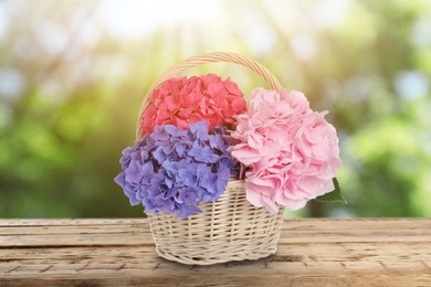 Image of Bouquet with beautiful hortensia flowers in wicker basket on wooden table outdoors. Bokeh effect