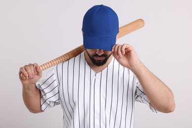 Man in stylish blue baseball cap holding bat on white background