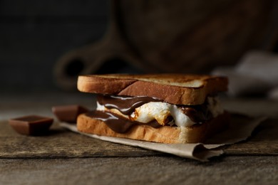 Photo of Delicious marshmallow sandwich with bread and chocolate on wooden table, closeup