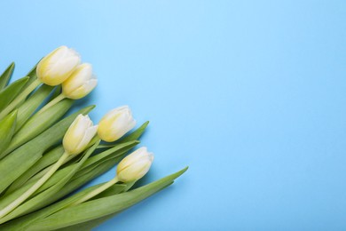 Photo of Beautiful yellow tulips on light blue background, flat lay. Space for text