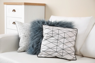 Different soft pillows on sofa in room. Interior element