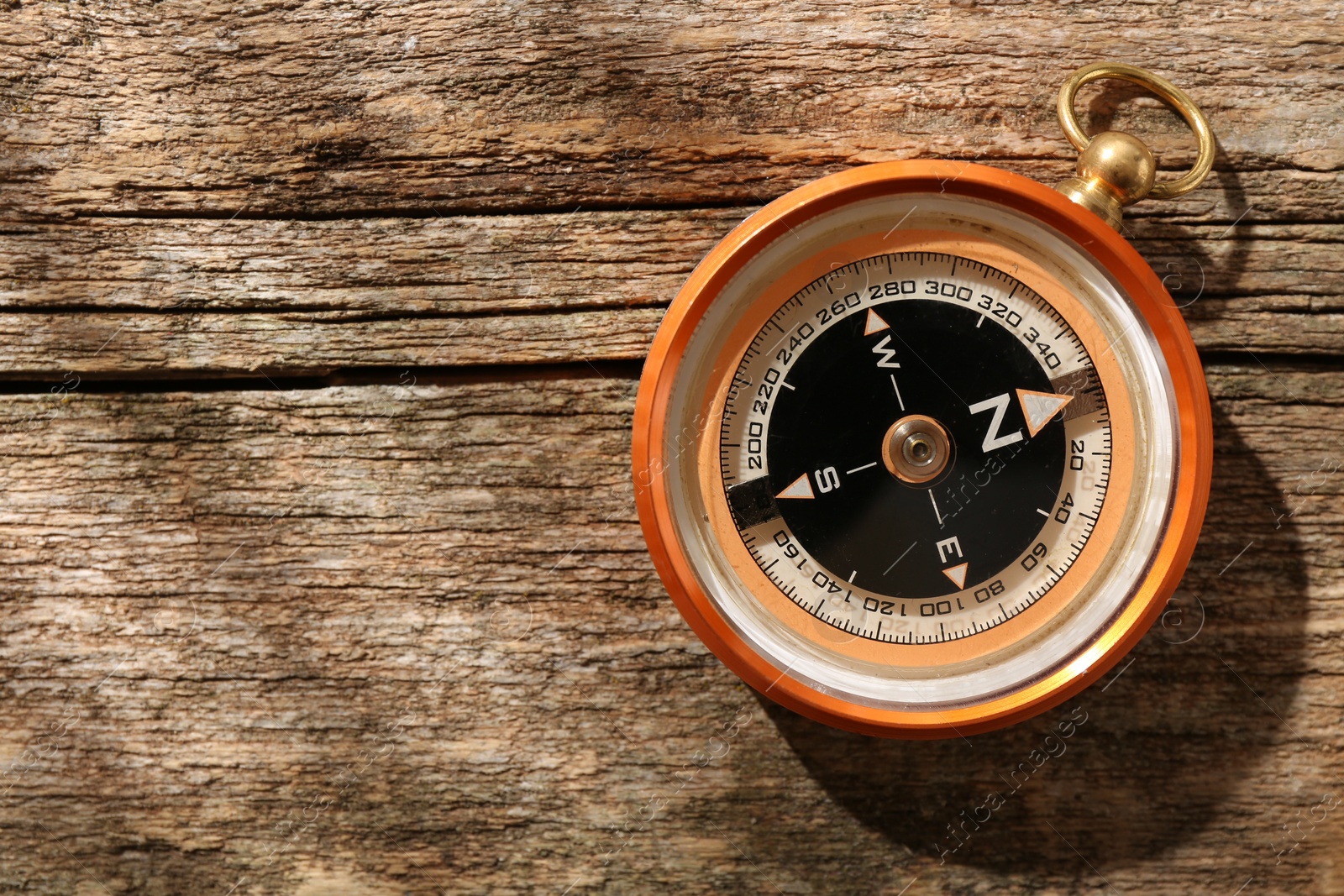 Photo of One compass on wooden table, top view. Space for text