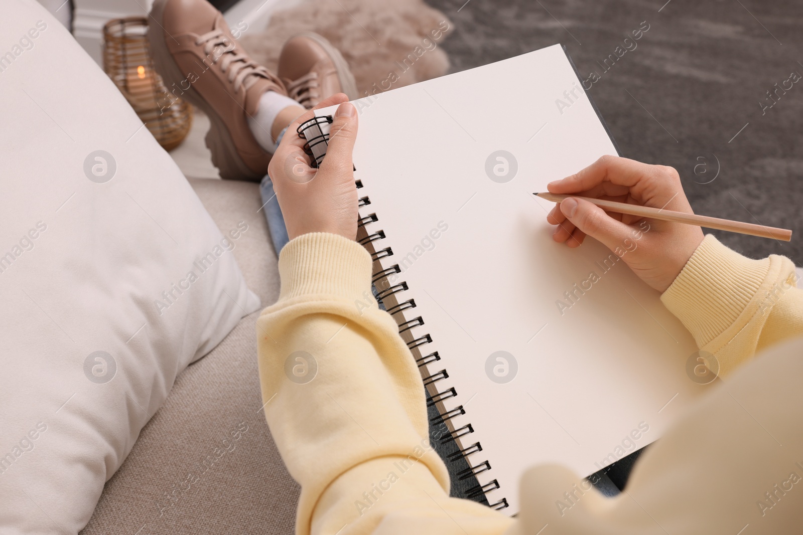 Photo of Young woman drawing in sketchbook indoors, closeup