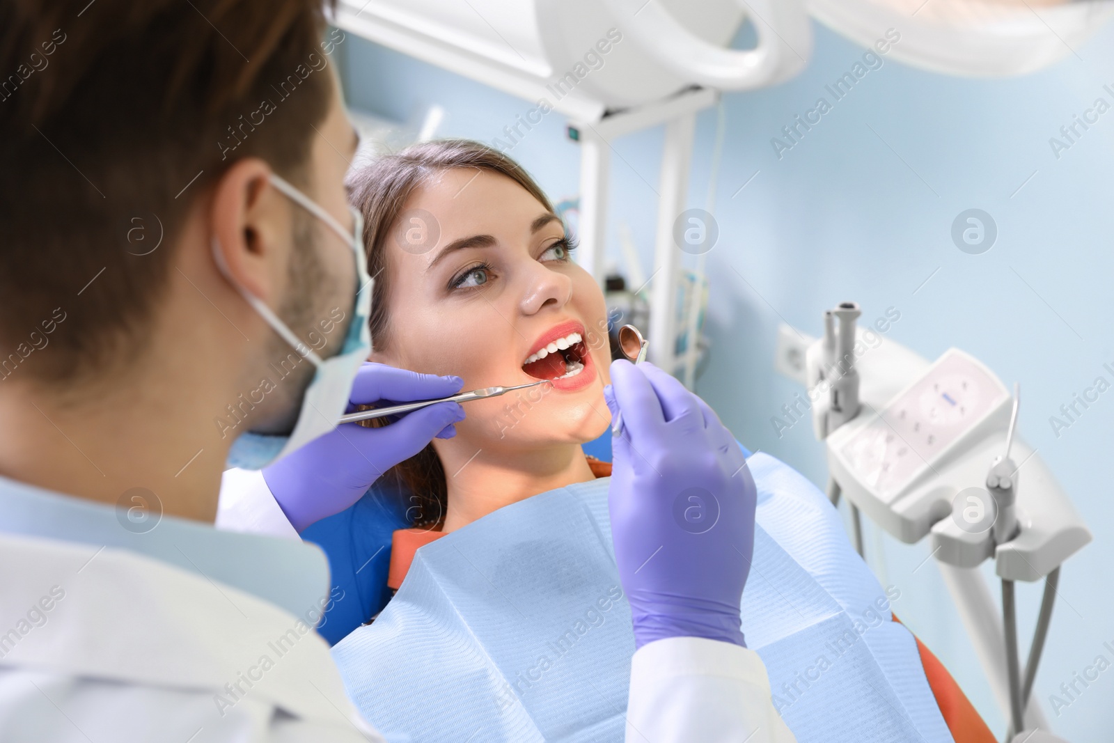 Photo of Professional dentist working with patient in modern clinic