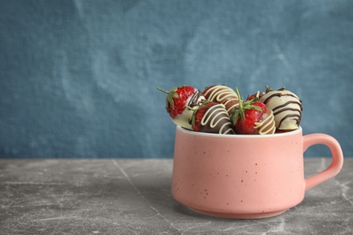 Photo of Cup with chocolate covered strawberries on table