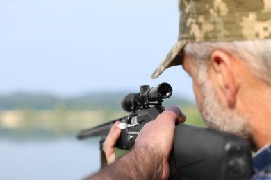 Photo of Man aiming with hunting rifle outdoors, closeup. Space for text