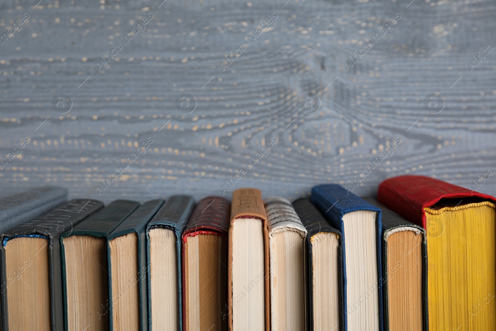 Photo of Stack of hardcover books on grey wooden background. Space for text