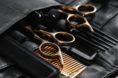 Photo of Hairdresser tools. Professional scissors and combs in leather organizer, closeup