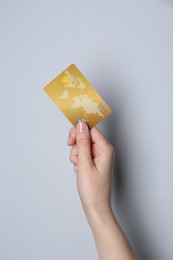 Woman holding credit card on light grey background, closeup