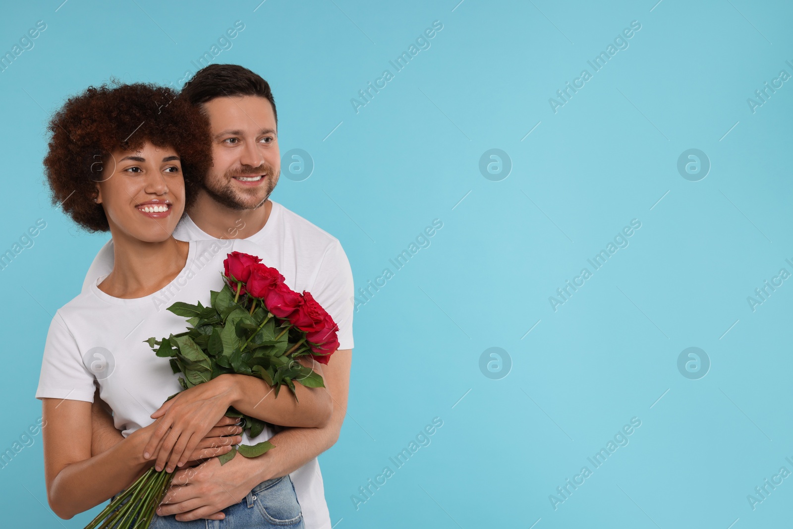 Photo of International dating. Happy couple with bouquet of roses on light blue background, space for text