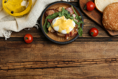 Delicious egg Benedict served on wooden table, flat lay. Space for text