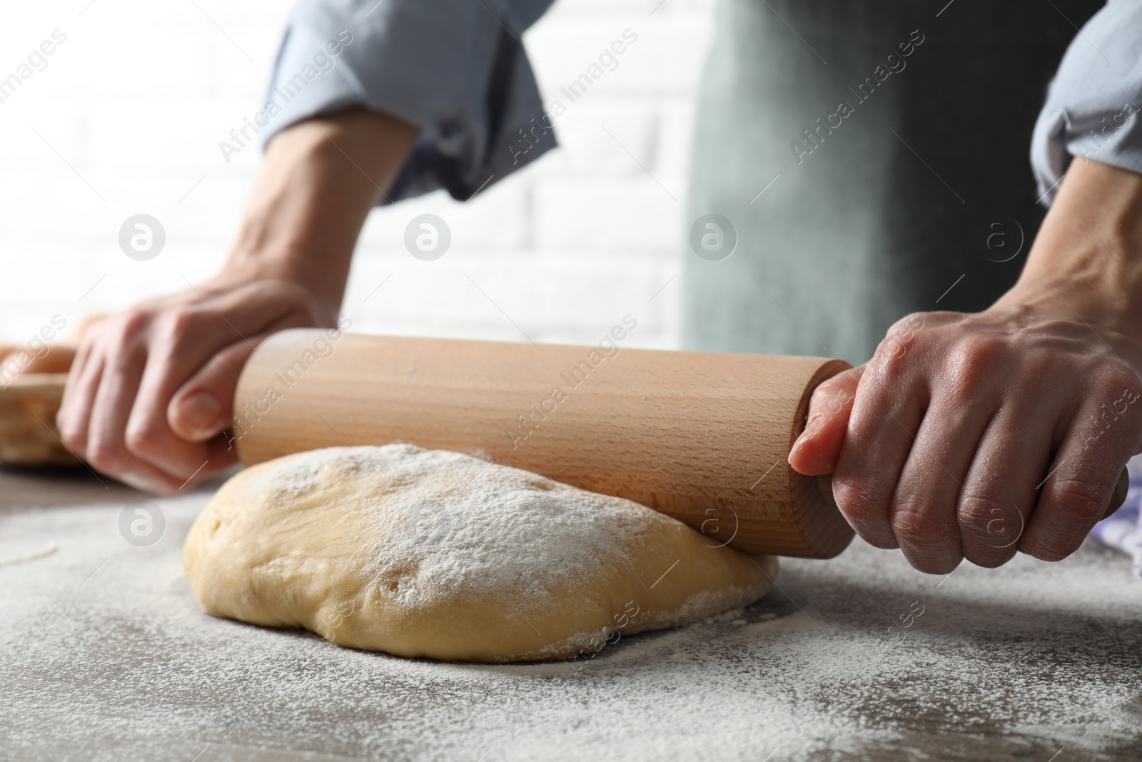 Photo of Woman rolling raw dough at table, closeup