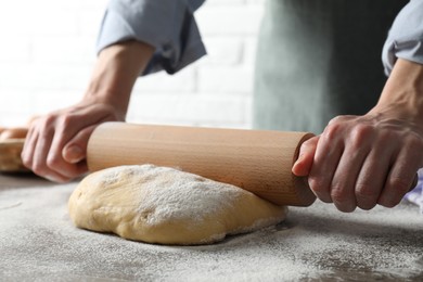 Photo of Woman rolling raw dough at table, closeup