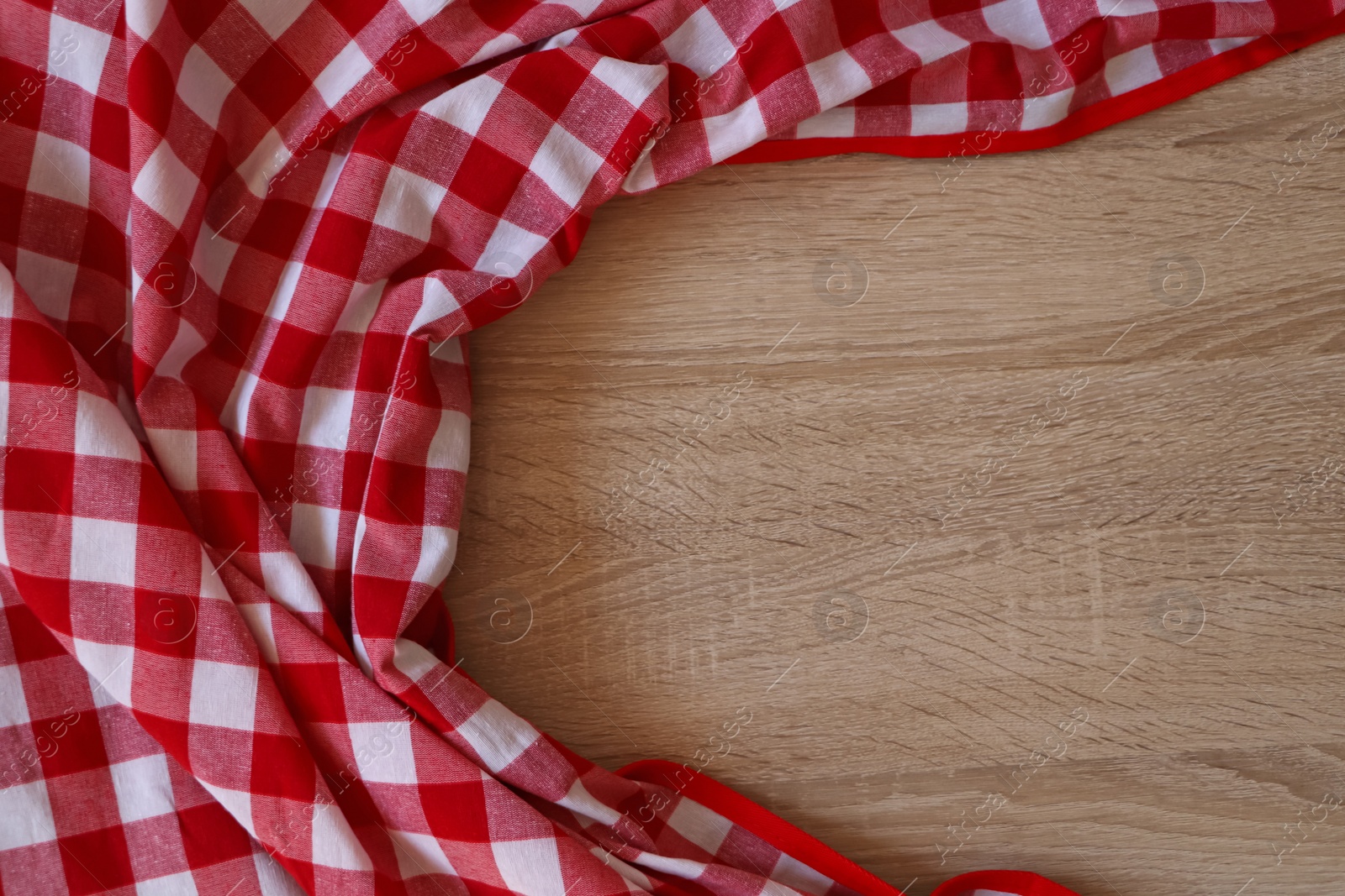 Photo of Checkered picnic cloth on wooden table, top view. Space for text