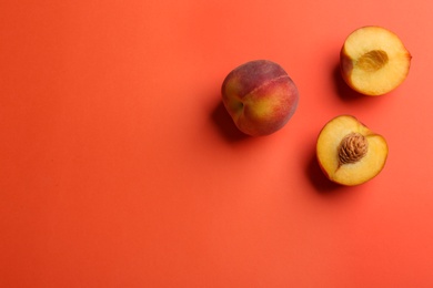 Photo of Flat lay composition with fresh peaches on coral background. Space for text