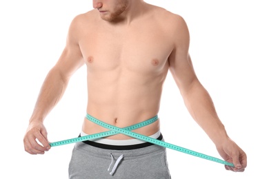 Young man with measuring tape showing his slim body on white background, closeup