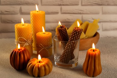 Photo of Beautiful burning beeswax candles on light textured table