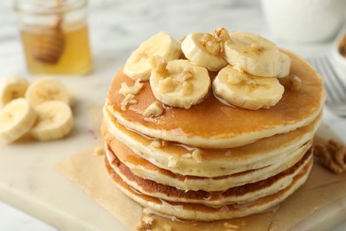 Photo of Delicious pancakes with bananas, walnuts and honey on table, closeup