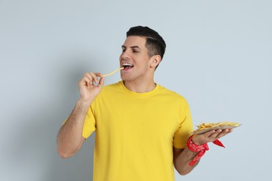Photo of Man eating French fries on grey background