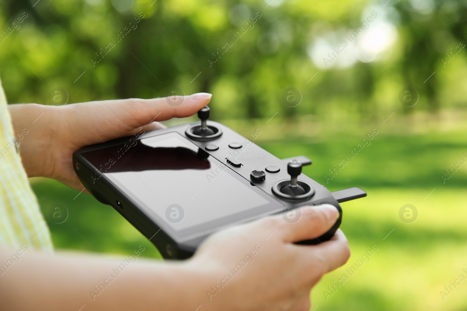 Photo of Woman holding new modern drone controller outdoors, closeup of hands