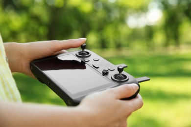 Photo of Woman holding new modern drone controller outdoors, closeup of hands