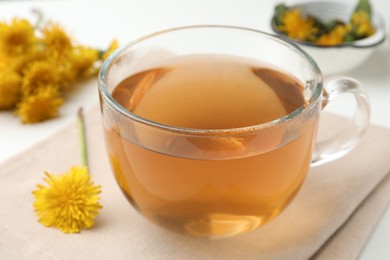 Delicious fresh tea and dandelion flowers on white table, closeup