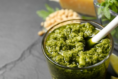 Glass of tasty arugula pesto on black table, closeup