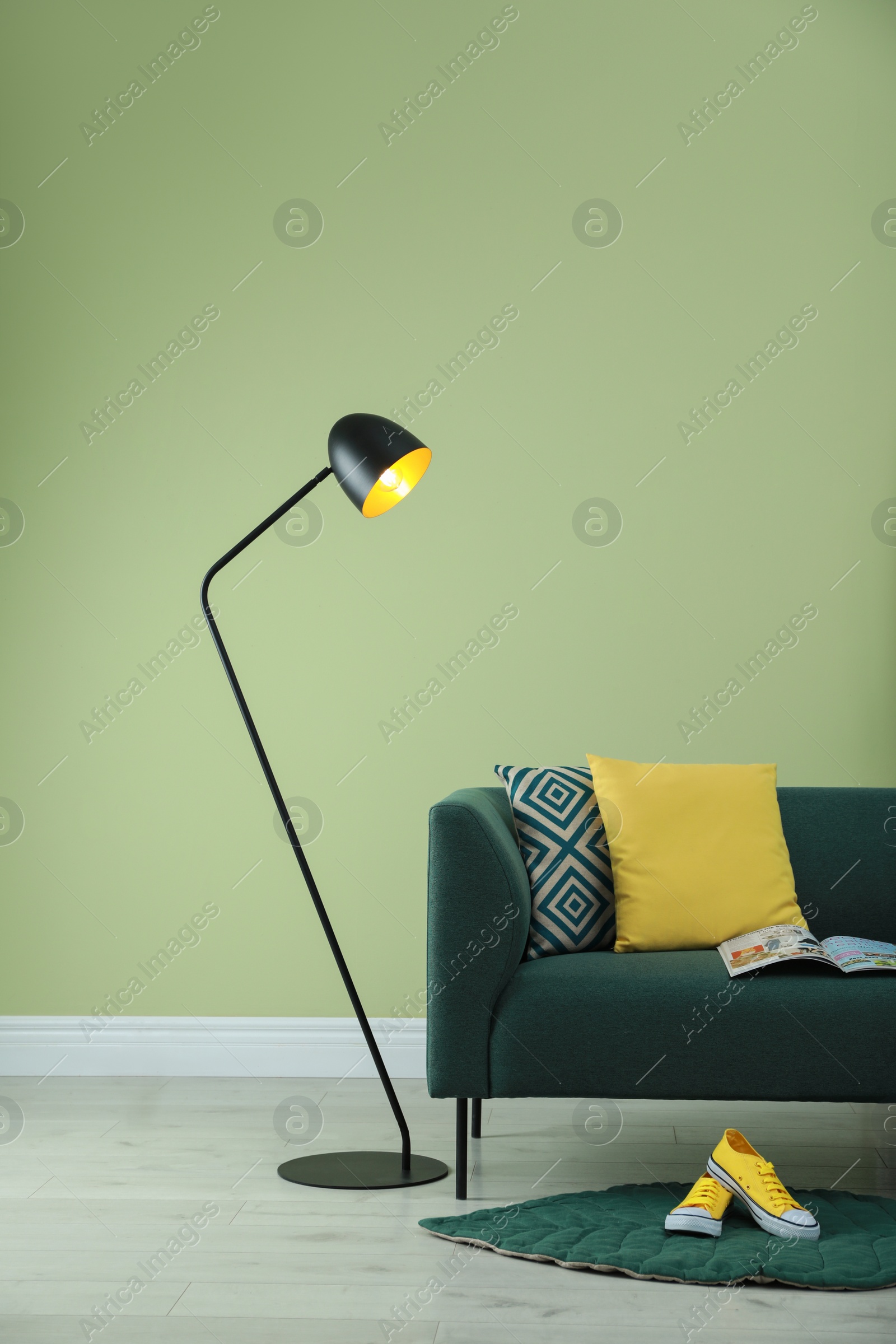 Photo of Stylish room living interior with comfortable sofa and lamp near green wall