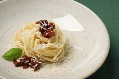 Photo of Tasty spaghetti with sun-dried tomatoes and parmesan cheese on table, closeup. Exquisite presentation of pasta dish