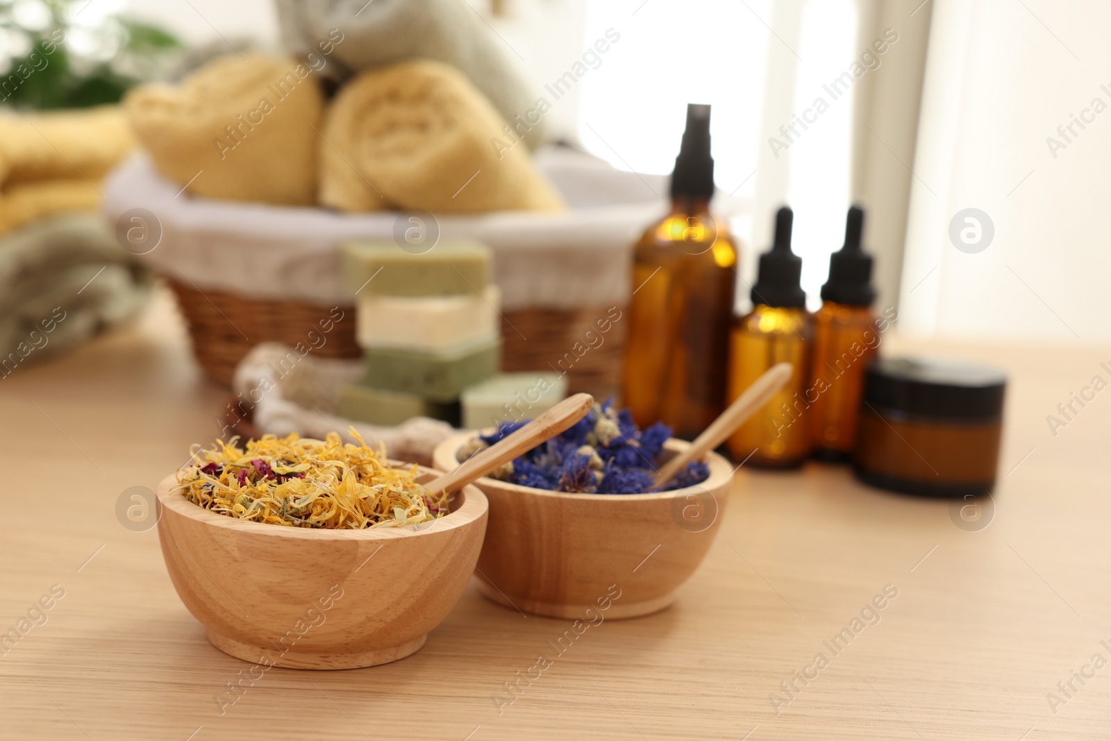 Photo of Bowls with dry flowers on wooden table indoors, space for text. Spa time