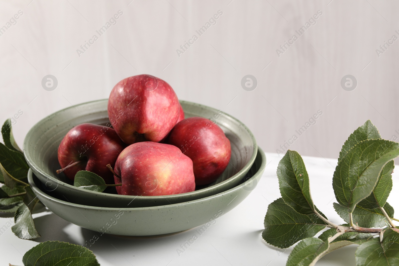 Photo of Fresh red apples and leaves on white table