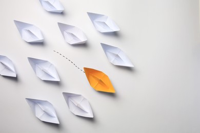 Photo of Yellow paper boat among others on white background, space for text. Uniqueness concept