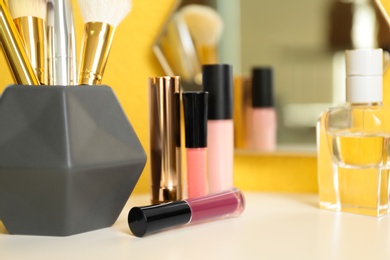 Photo of Lipsticks and holder with other makeup products on dressing table, space for text