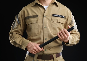 Male security guard with police baton on dark background