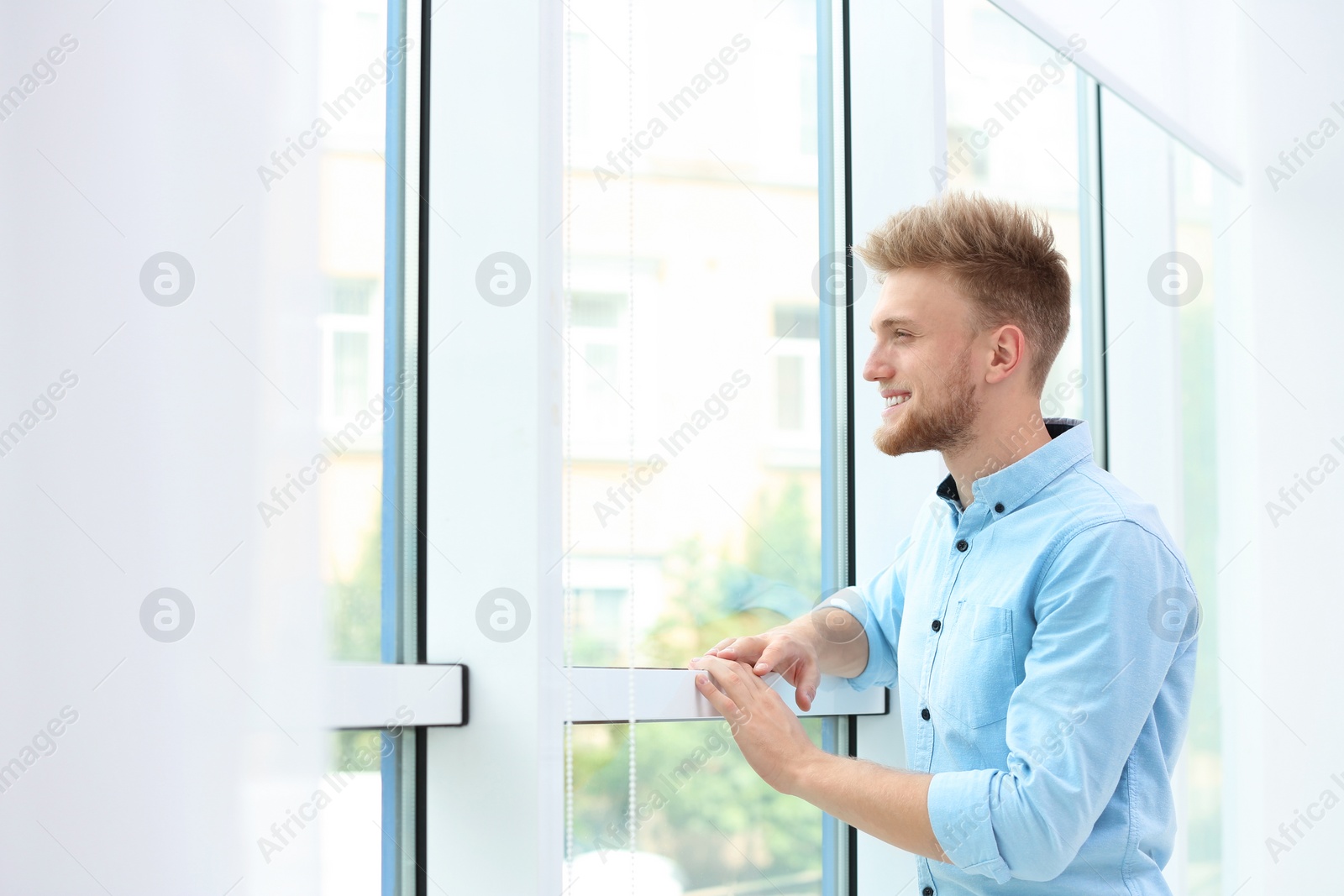 Photo of Portrait of handsome young man looking out window indoors