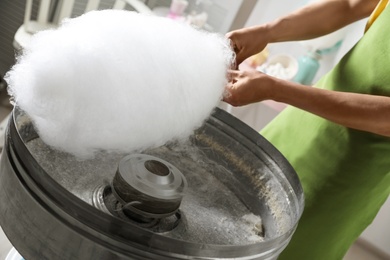 Photo of Woman making cotton candy using modern machine indoors, closeup