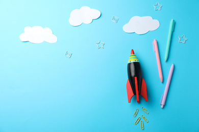 Photo of Bright toy rocket and school supplies on light blue background, flat lay. Space for text