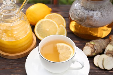 Cup of delicious tea with lemon and honey on wooden table