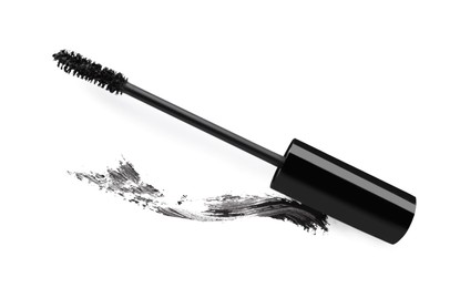 Applicator brush and brown mascara stroke on white background, top view