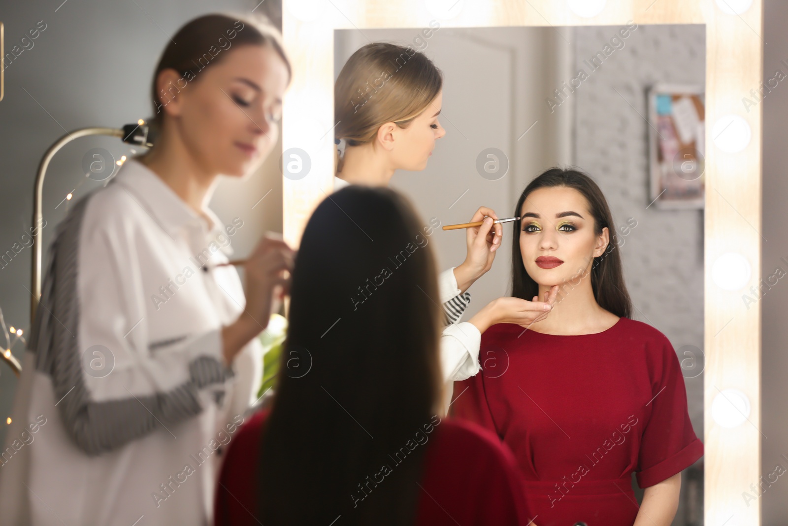 Photo of Professional visage artist applying makeup on woman's face in salon