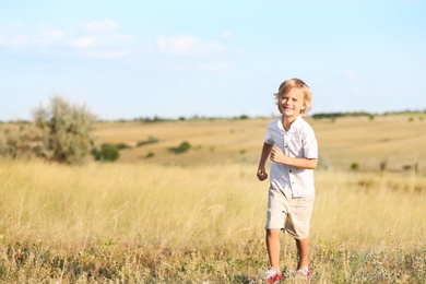 Photo of Cute little boy outdoors, space for text. Child spending time in nature