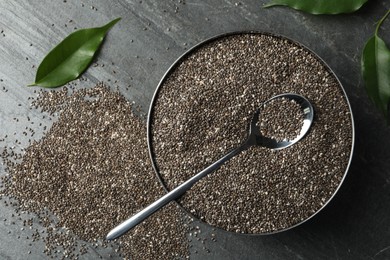 Metal bowl with chia seeds and spoon on slate table, flat lay