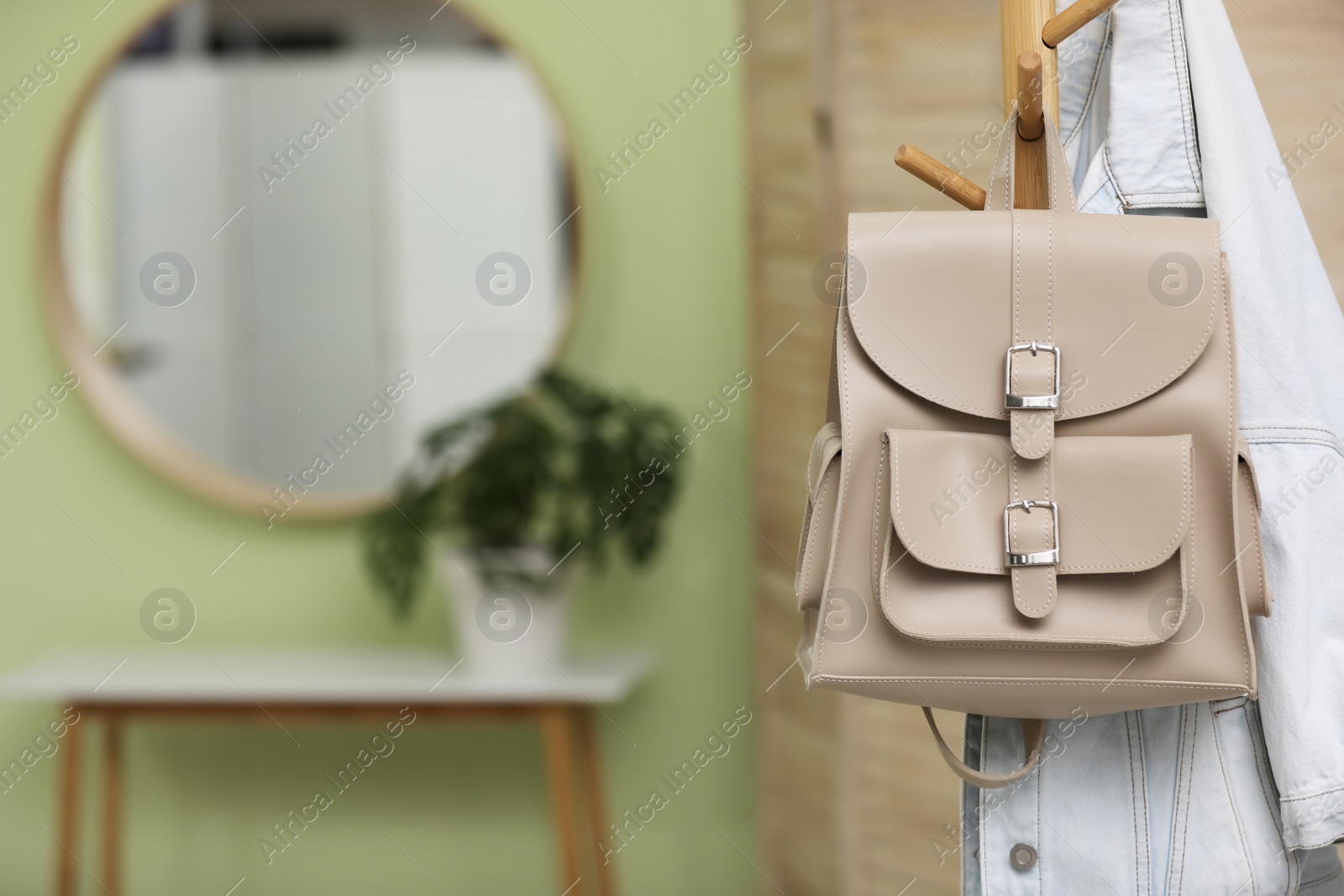 Photo of Stylish beige backpack and jacket hanging on clothes rack indoors, space for text