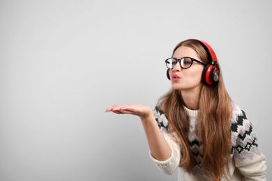 Young woman listening to music with headphones on grey background, space for text