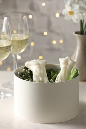 Champagne and gift box with beautiful sculptural candles on white table