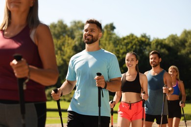 Photo of Group of people practicing Nordic walking with poles outdoors on sunny day