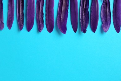 Photo of Purple feathers on light blue background, flat lay. Space for text