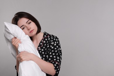Photo of Unhappy young woman with pillow on light grey background, space for text. Insomnia problem